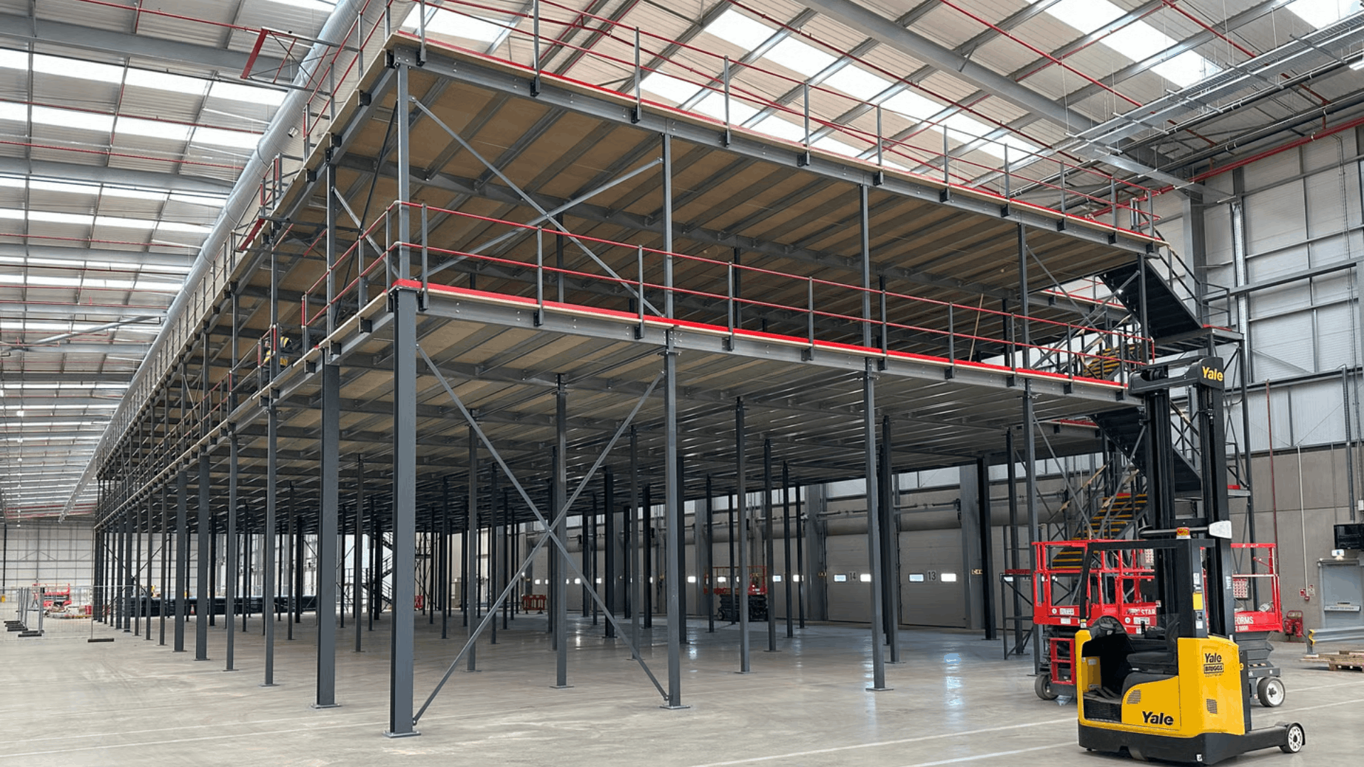 Completed two-tier mezzanine floor installation for Ziegler at London Gateway, showing steel columns, red handrails, staircase access and warehouse floor space below