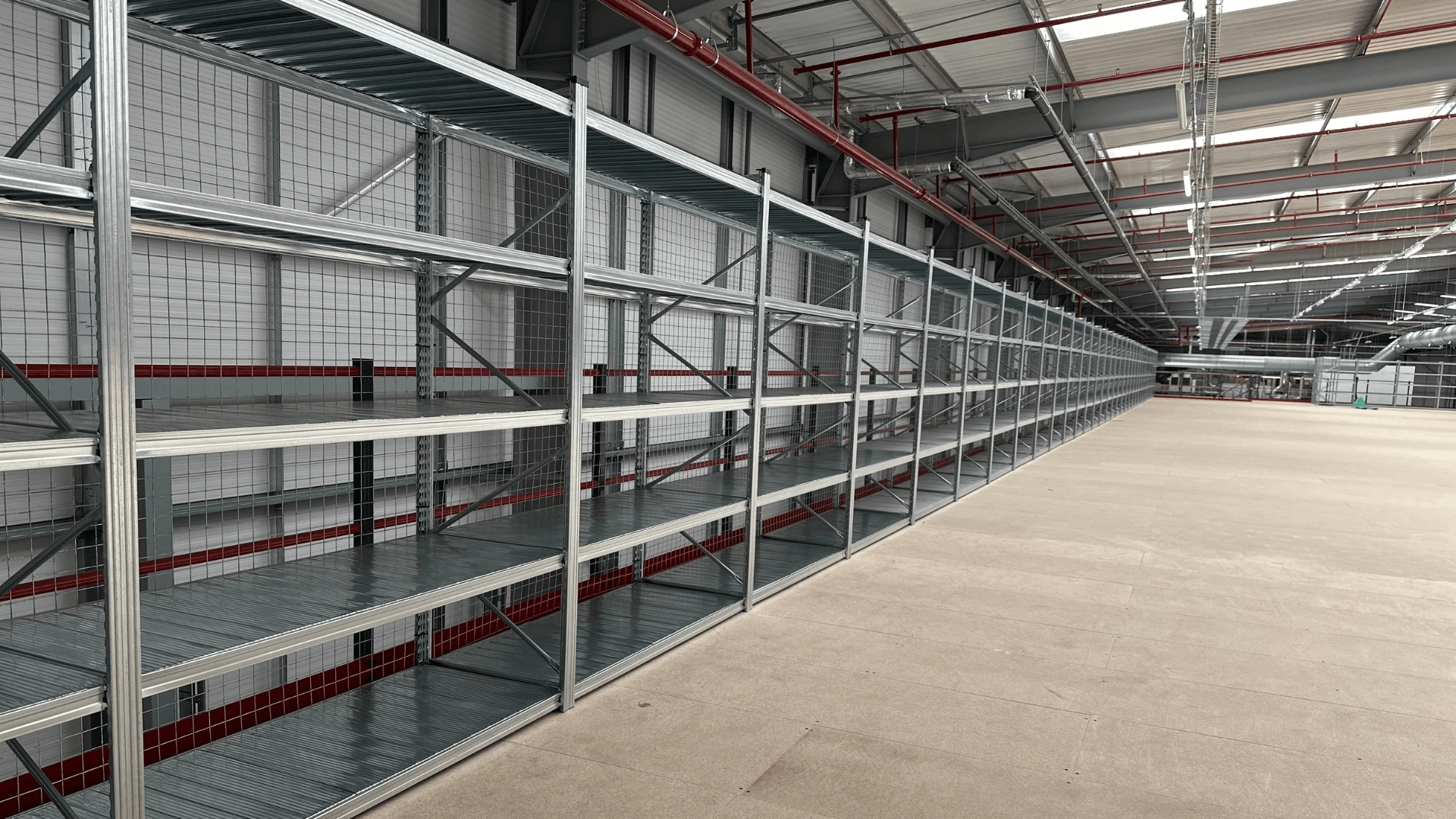 Storage racking installed along the upper mezzanine floor at Ziegler, with galvanised shelving, mesh backing and red perimeter handrails