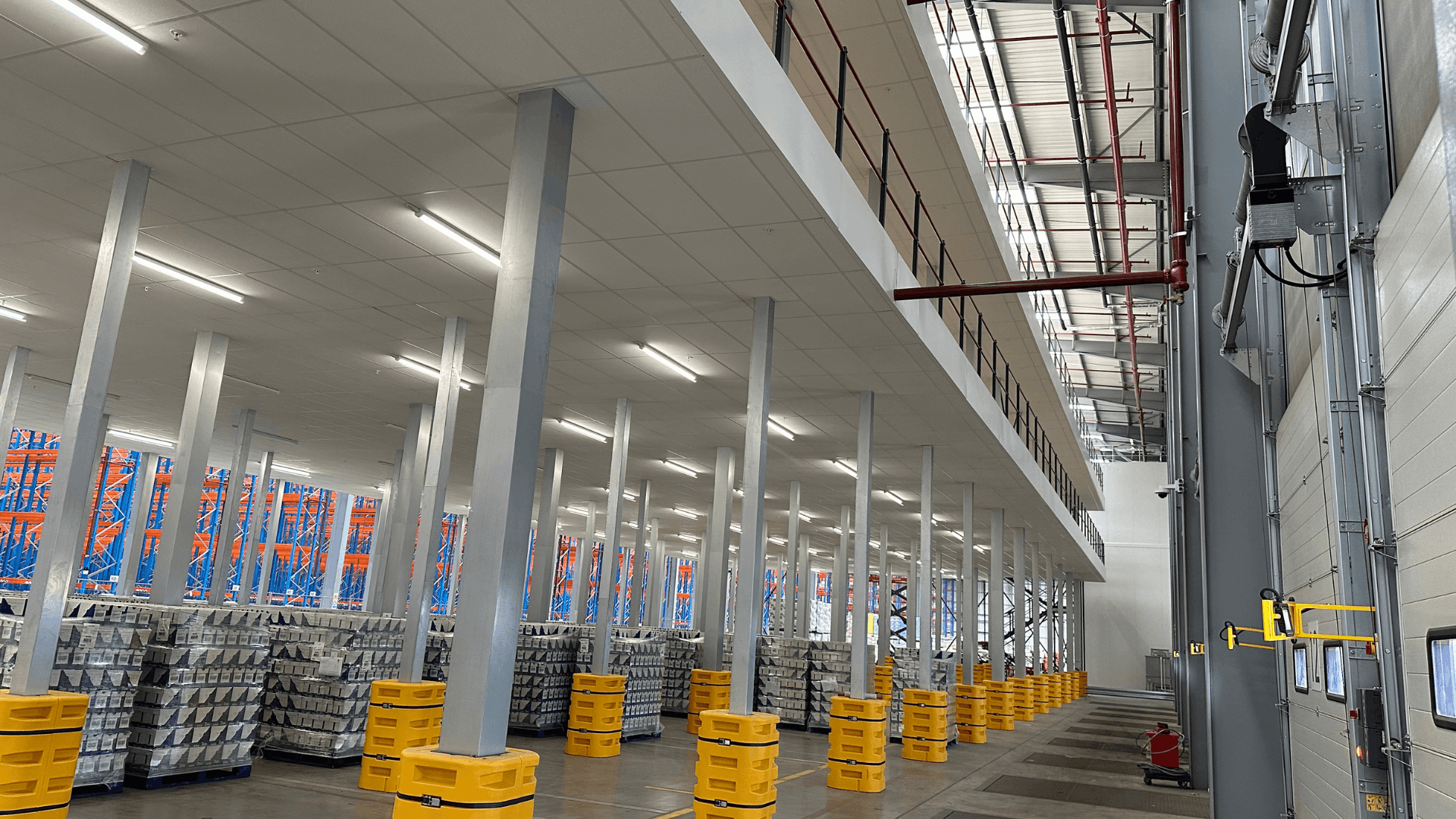 Side view of completed Ziegler mezzanine structure with fire-rated ceiling, steel support columns, red edge protection and warehouse loading bays